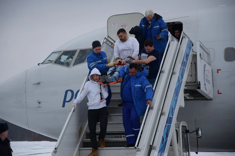 Богдан (на переднем плане в белой куртке) вместе с еще двумя пассажирами и медиками выносит больного.