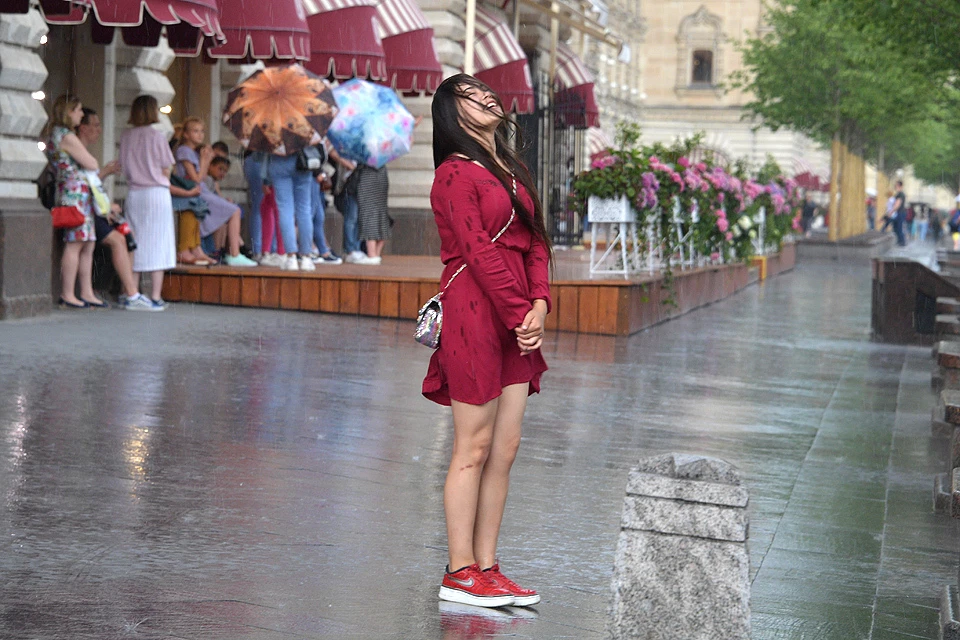 Китайская туристка охлаждается под дождиком возле Красной площади.