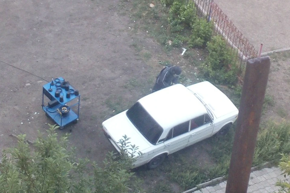 Сапер осматривает машину после взрыва. С этого ракурса авто выглядит целым.