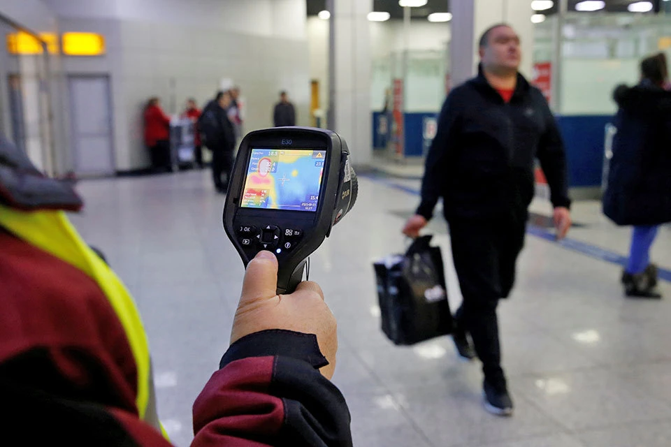 В международном аэропорту в Казахстане работник санитарно-эпидемиологический службы проверяет тепловизором пассажиров.