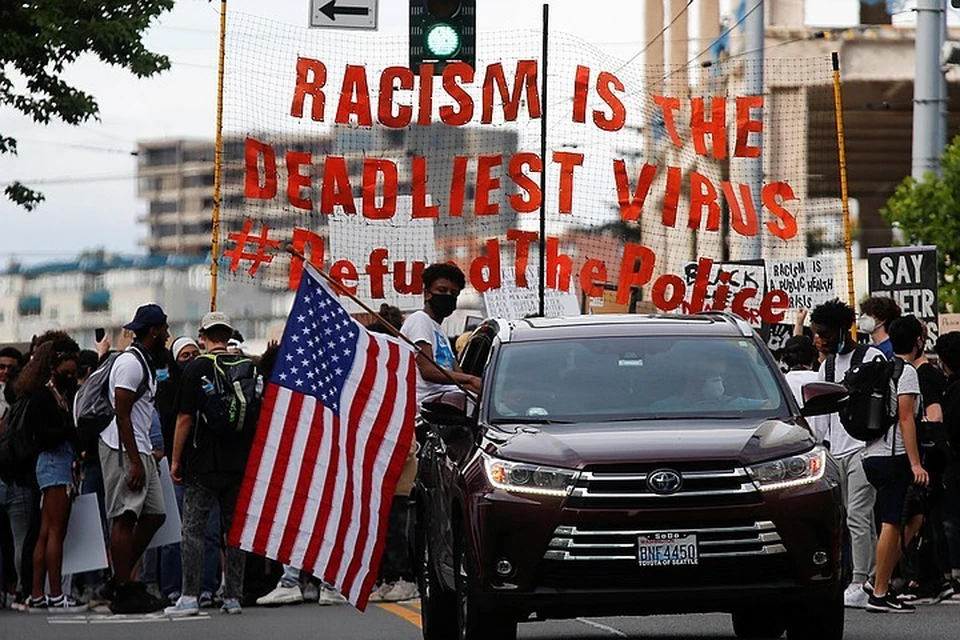Участники протестов выходят под лозунгом о том, что "расизм - самый смертельный вирус" и требуют урезать полицейское финансирование.