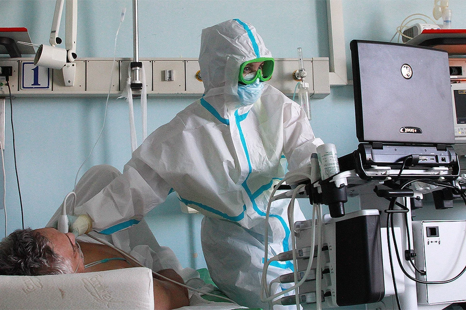 Врач обследует пациента отделения для зараженных коронавирусной инфекцией COVID-19 в больнице Иркутска.