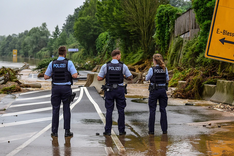 Полицейские у разрушенной водой автотрассы в городе Эрфтштадт, Германия.
