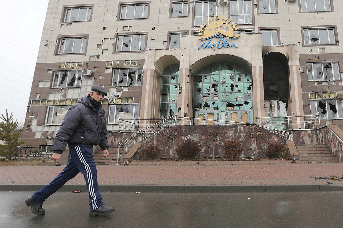 Мужчина проходит мимо разгромленного офиса правящей казахстанской партии Нур Отан в городе Алматы.