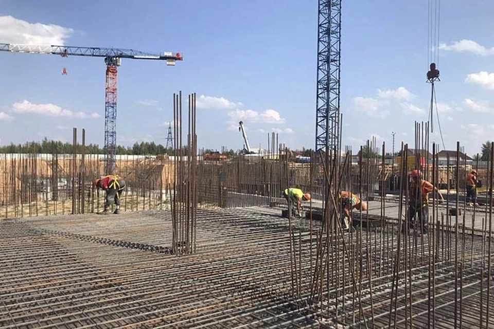 Фундамент здания уже готов, рабочие устанавливают каркас