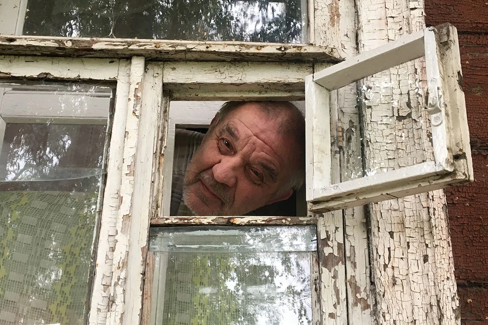 Виктор Мохов в окошке своего дома. Он очень доволен вниманием журналистов.