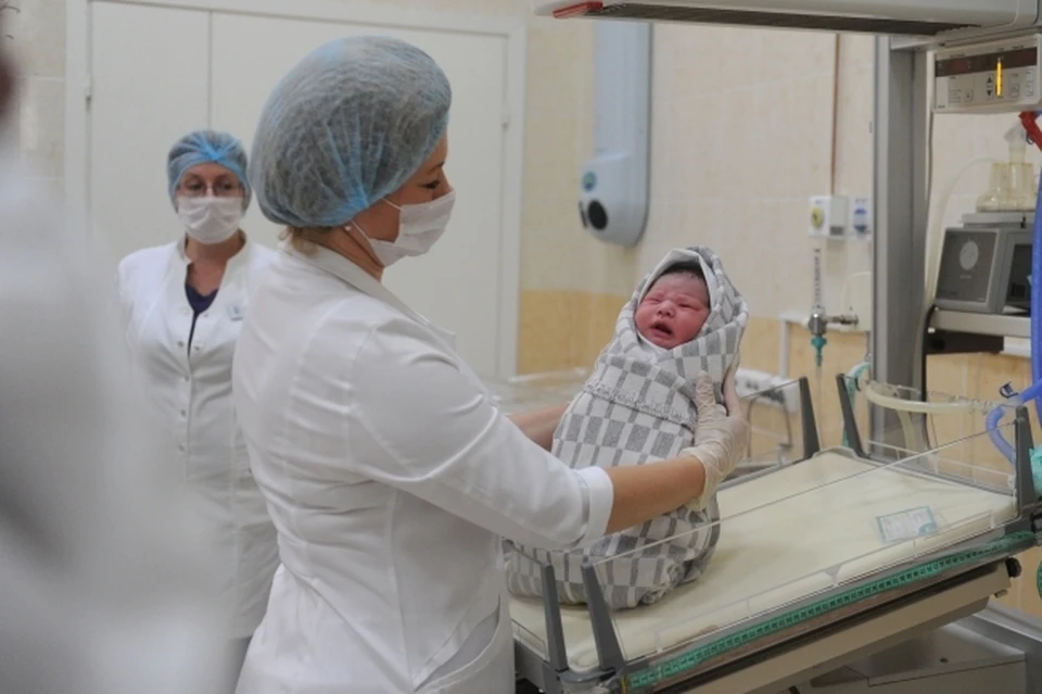 Медицинский работник осматривает новорожденного ребенка