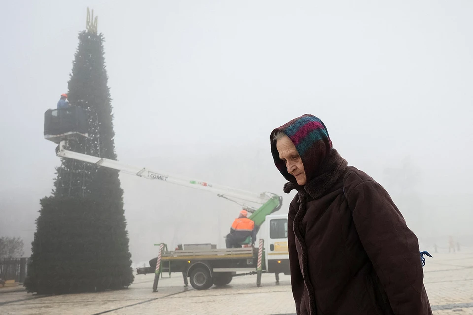 Киевлянка на фоне новогодней елки, устанавливаемой в центре украинской столицы.