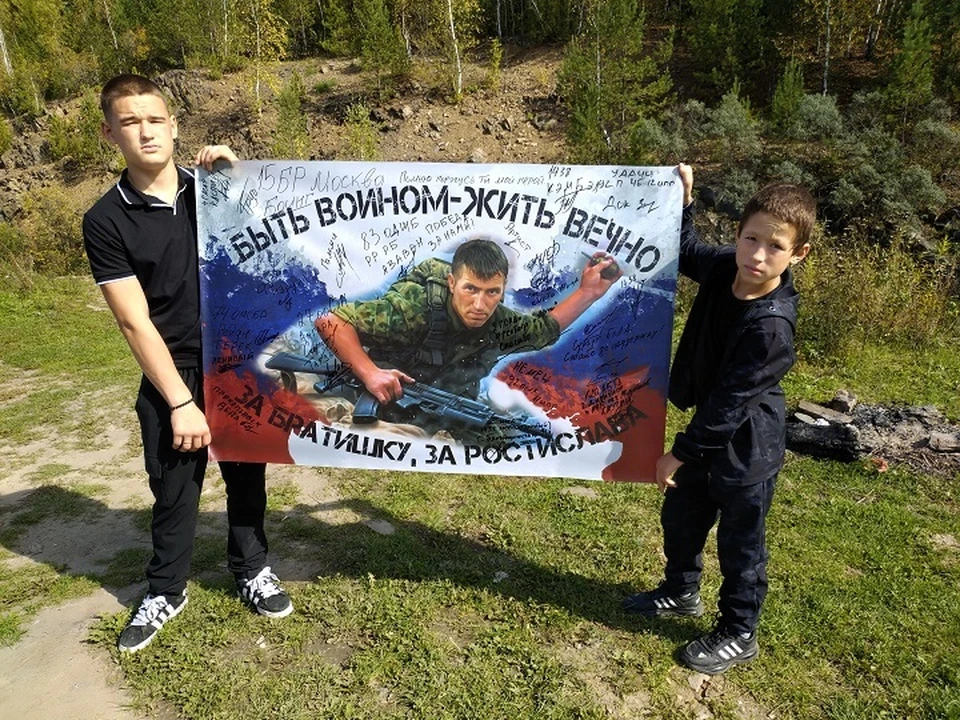 Станислав и Антон Трутневы с флагом с портретом дяди Ростика, бойца-героя СВО.