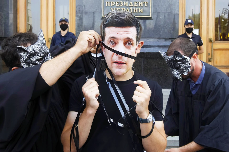 Украинские активисты изображают Зеленского и судей-волков, которые символически оборачивают его пленкой с аудиозаписями, полученными НАБУ