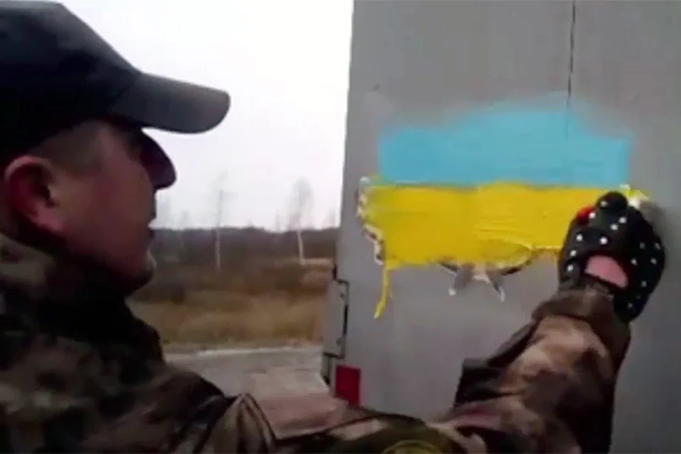 На кадрах щекастые здоровяки в разношерстных камуфляжных костюмах малюют на прицепе российской фуры украинский флаг