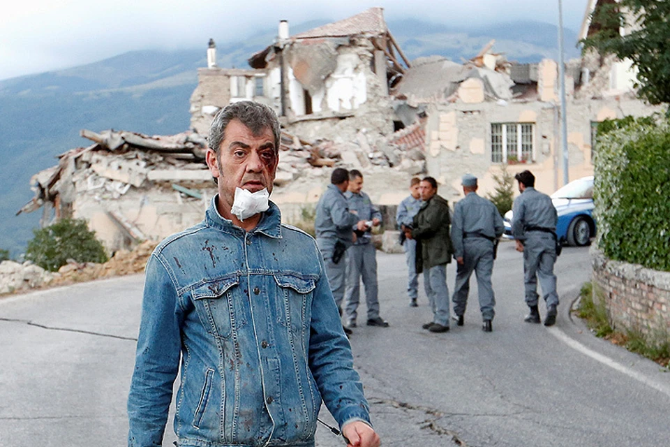 Житель итальянского города Аматриче проходит мимо разрушенного землетрясением здания.