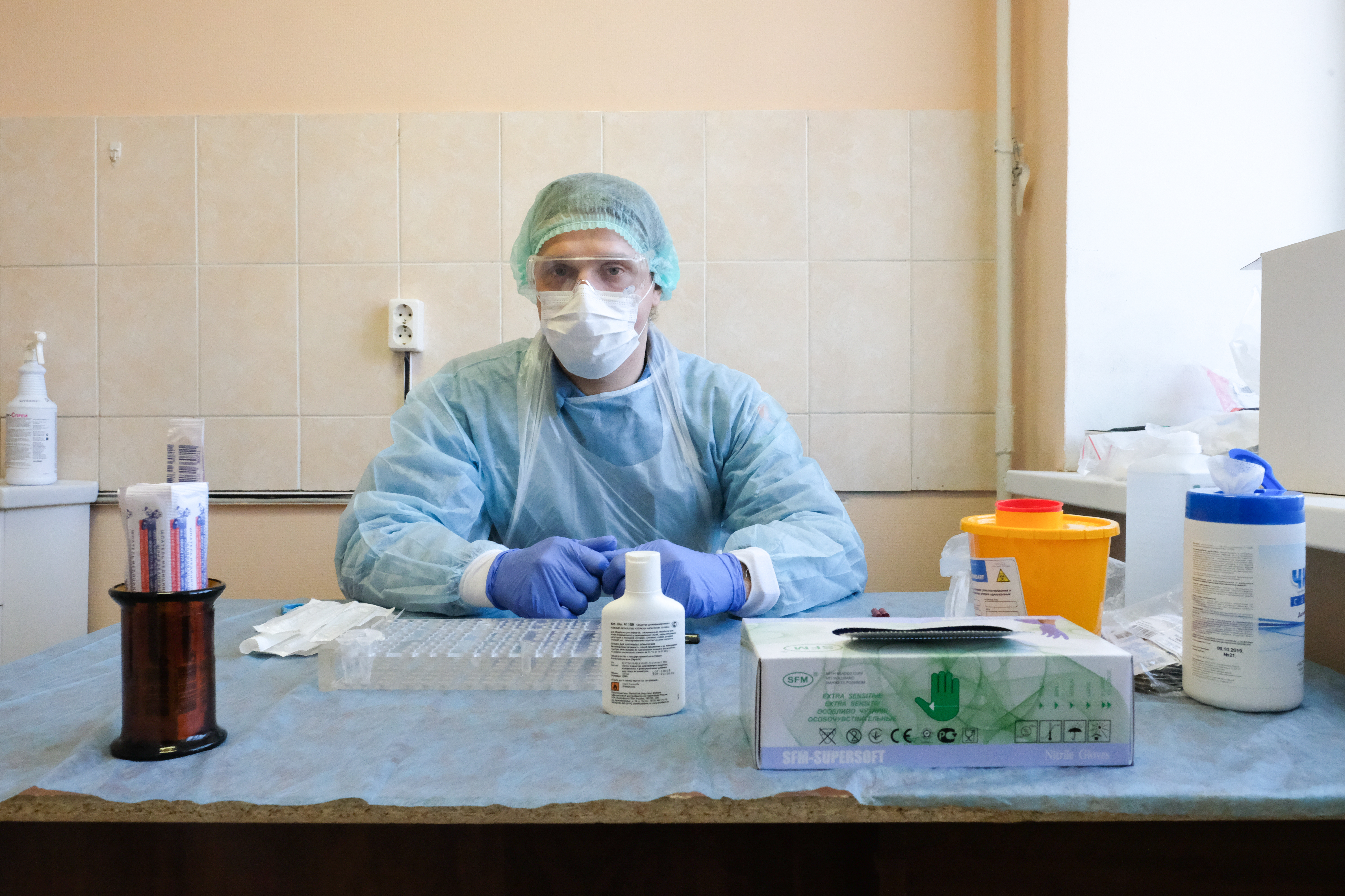 Специалисты ведут прием в защитной одежде.
